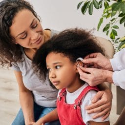 Little girl with her mother going in for a hearing aid fitting.