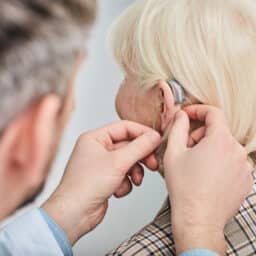 Older woman getting fitted for a hearing aid.