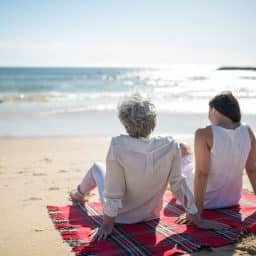 Two women sitting together on the beach.