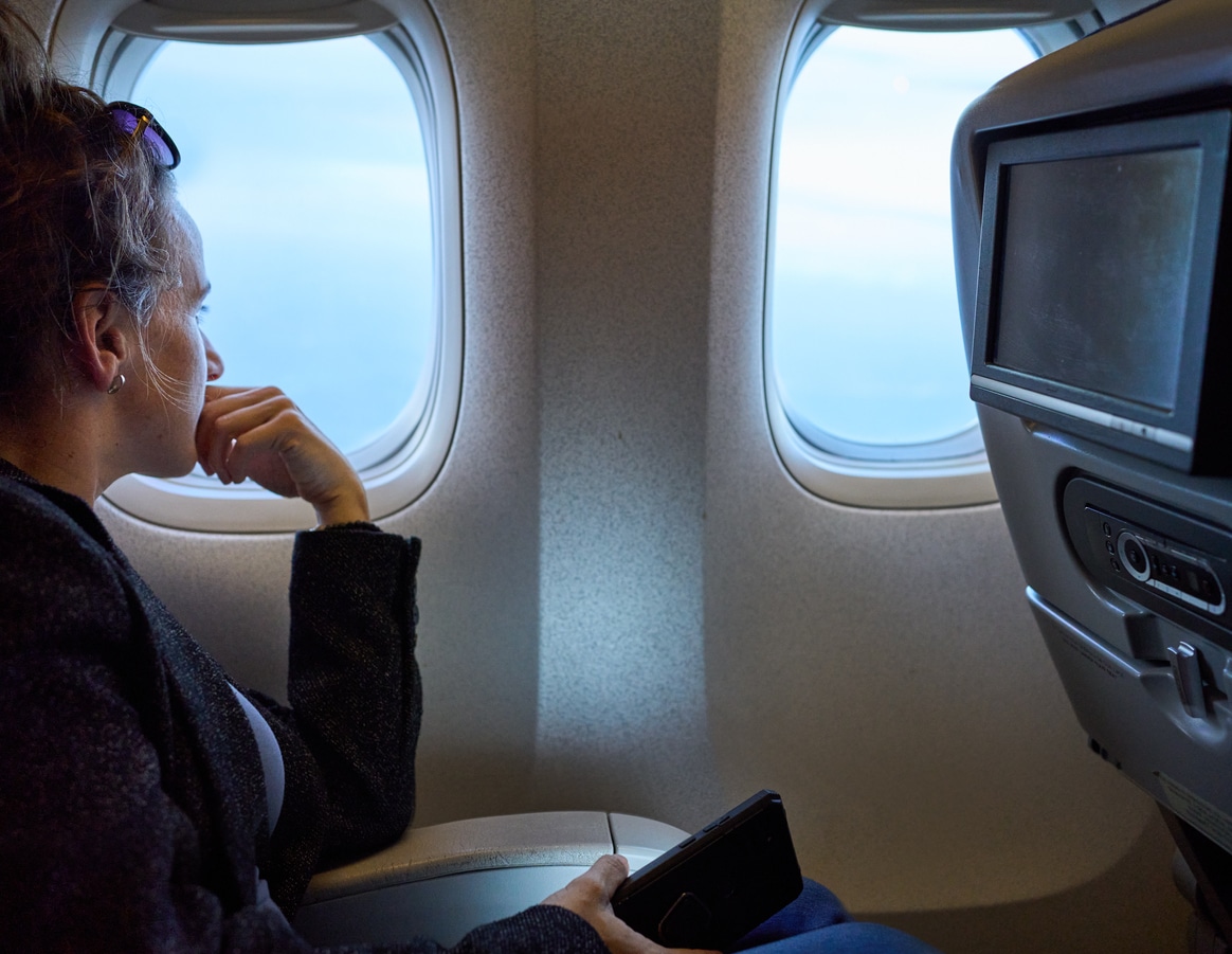 Woman traveler on the plane looking out of the window Side view of a woman traveling in plane and looking out of the window