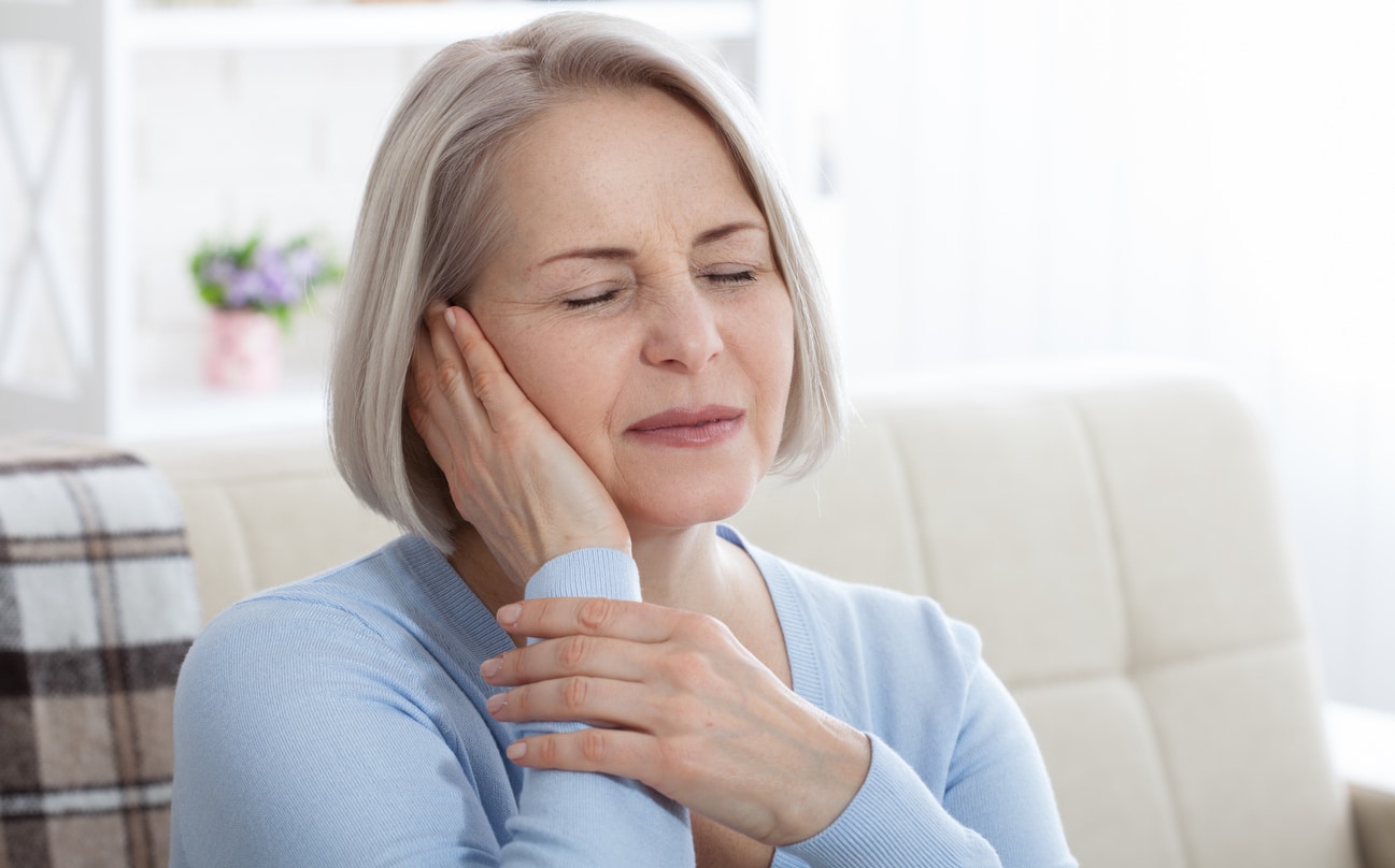 Woman with ear pain holds hand to ear Woman with ear pain holds hand to ear