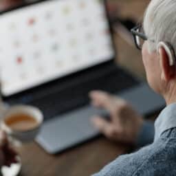 Senior man wearing a hearing aid using his laptop