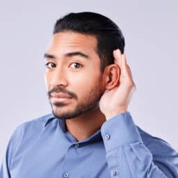 Man with hearing loss holding a hand up to his ear. 