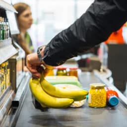 Person putting bananas on the grocery store conveyor belt.