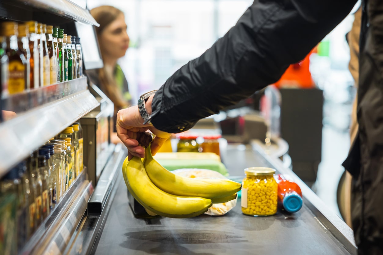 Person putting bananas on the grocery store conveyor belt.