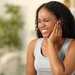 Woman with tinnitus holds her ear looking uncomfortable. Woman with tinnitus holds her ear looking uncomfortable.