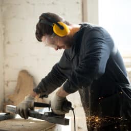 Worker in a woodshop wears hearing protection to prevent noise-induced hearing loss. Worker in a woodshop wears hearing protection to prevent noise-induced hearing loss.