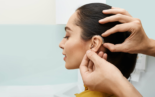 Young woman patient has her hearing aids professionally fitted by the audiologist