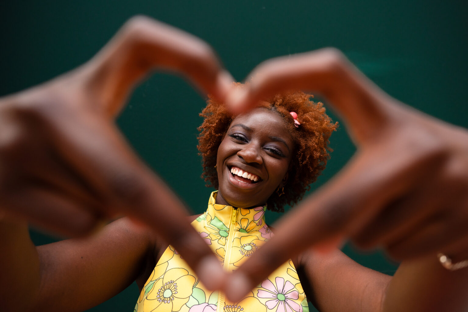 Smiling woman makes a heart shape with her fingers